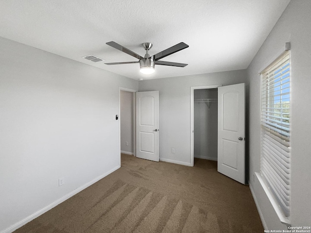 unfurnished bedroom with carpet flooring, a textured ceiling, ceiling fan, and a closet