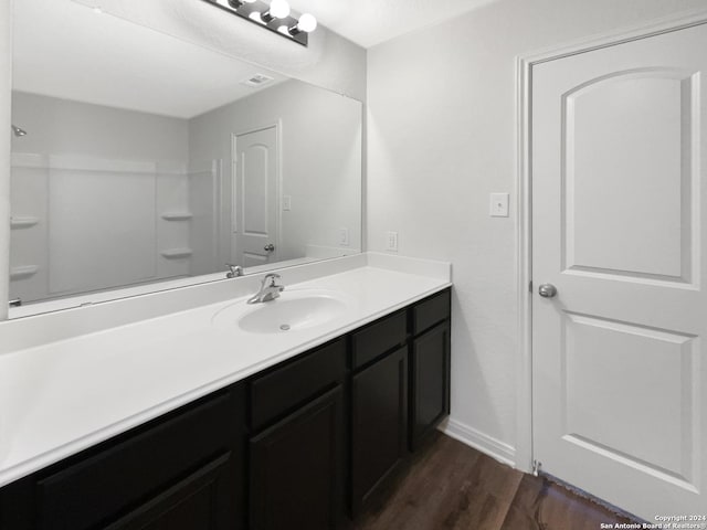 bathroom featuring vanity, wood-type flooring, and walk in shower