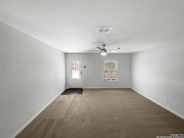 carpeted empty room featuring ceiling fan and a textured ceiling