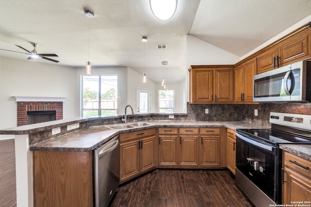 kitchen with ceiling fan, stainless steel appliances, dark hardwood / wood-style flooring, sink, and a brick fireplace