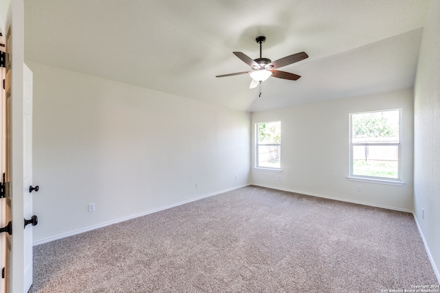 carpeted spare room with ceiling fan and vaulted ceiling