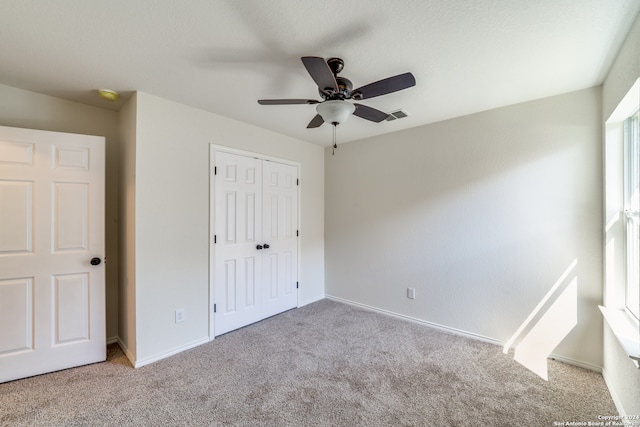 unfurnished bedroom featuring light colored carpet, a closet, and ceiling fan