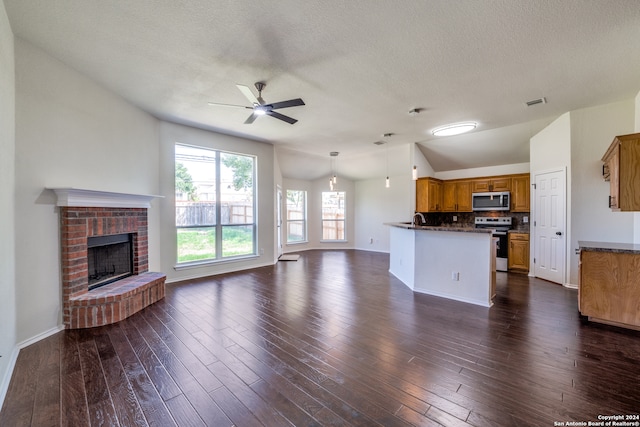 unfurnished living room featuring a fireplace, dark hardwood / wood-style flooring, a textured ceiling, lofted ceiling, and ceiling fan