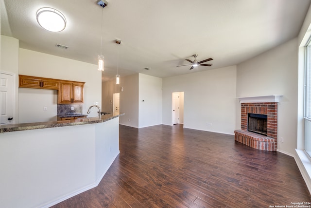 kitchen with dark stone counters, dark hardwood / wood-style floors, a fireplace, and ceiling fan