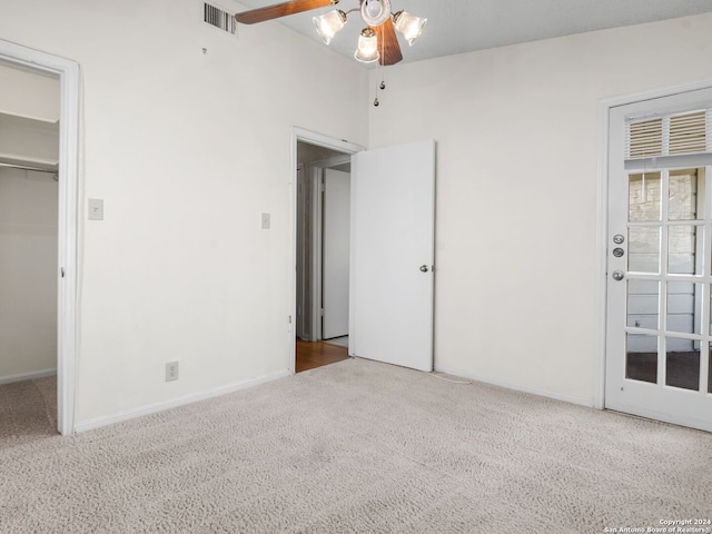 unfurnished bedroom with a spacious closet, a closet, carpet floors, lofted ceiling, and ceiling fan