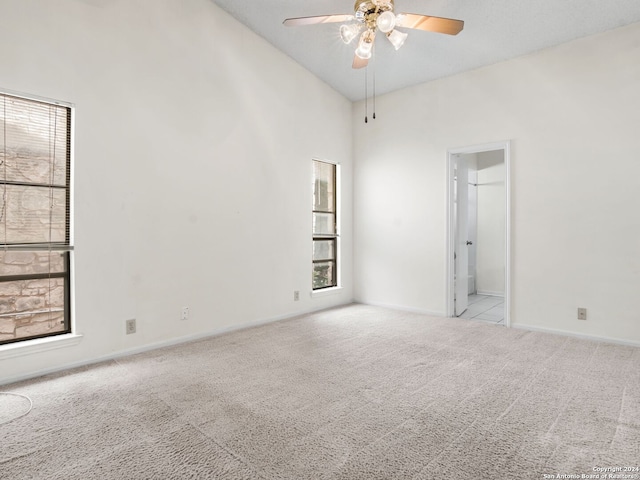 carpeted spare room featuring high vaulted ceiling and ceiling fan