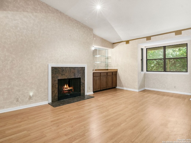 unfurnished living room featuring a fireplace, lofted ceiling, and light wood-type flooring