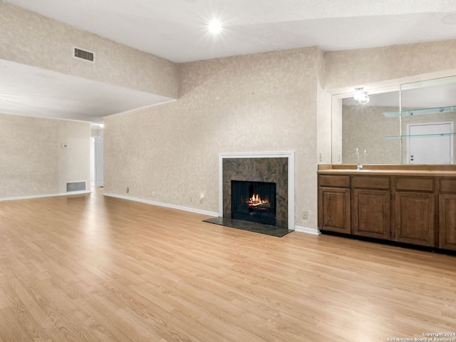 unfurnished living room featuring a high end fireplace and light hardwood / wood-style floors