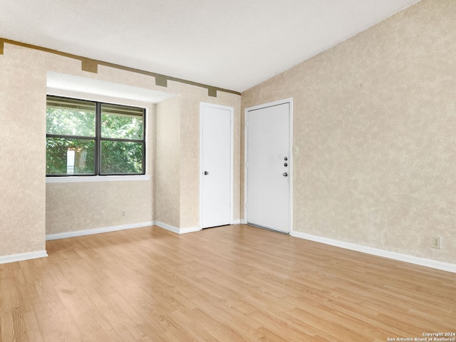 spare room with lofted ceiling and light hardwood / wood-style floors