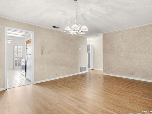 unfurnished room featuring a textured ceiling, light tile patterned floors, crown molding, and a chandelier