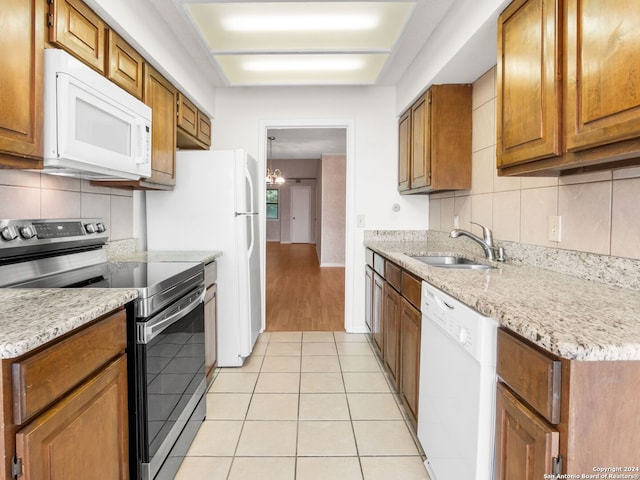 kitchen with light hardwood / wood-style flooring, white appliances, sink, light stone counters, and decorative backsplash