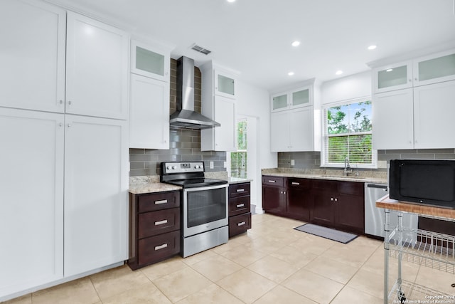 kitchen featuring dark brown cabinets, wall chimney range hood, backsplash, appliances with stainless steel finishes, and sink