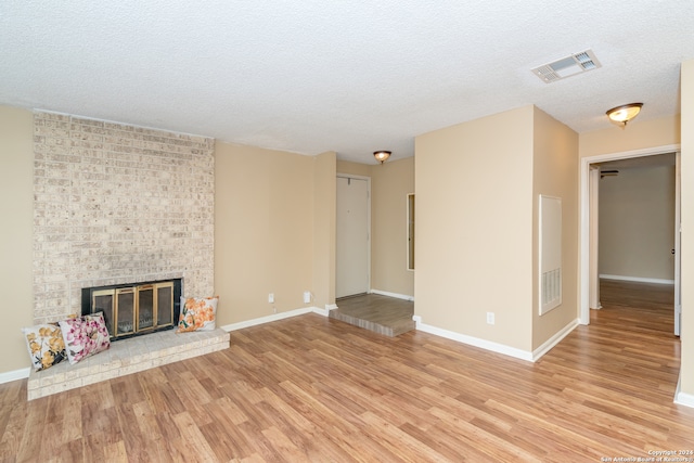 unfurnished living room featuring a textured ceiling, light hardwood / wood-style flooring, and a fireplace