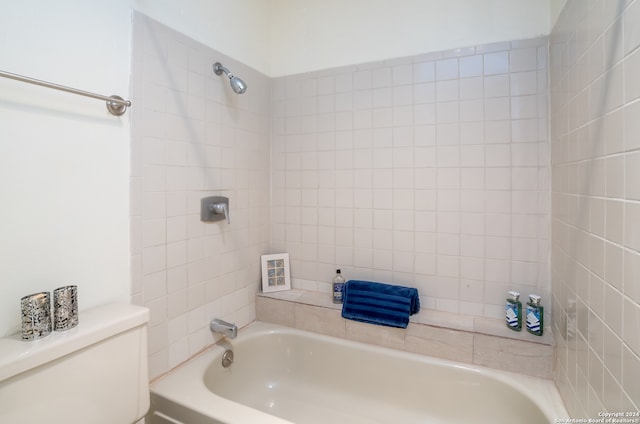 bathroom featuring toilet and tiled shower / bath