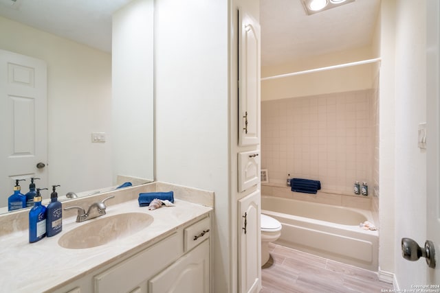 full bathroom featuring vanity, tiled shower / bath combo, and toilet