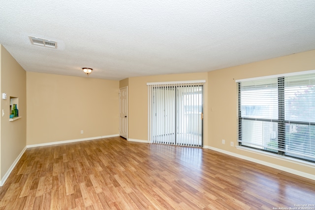 empty room with a textured ceiling and light wood-type flooring