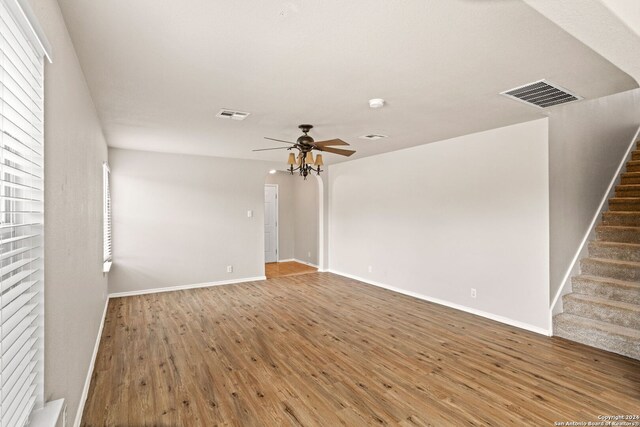 unfurnished living room with ceiling fan with notable chandelier and hardwood / wood-style floors