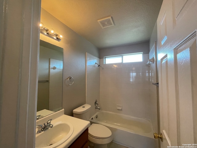 full bathroom with vanity, a textured ceiling, tiled shower / bath combo, and toilet