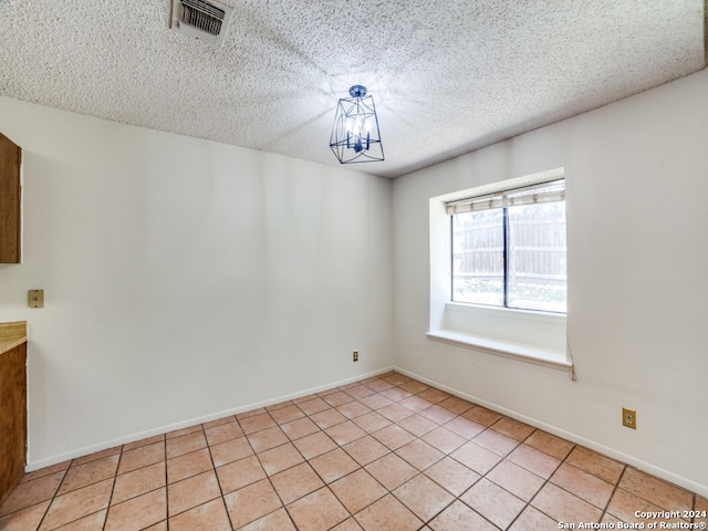 empty room with light tile patterned flooring and a textured ceiling