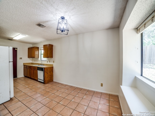 kitchen featuring white appliances, sink, light tile patterned floors, a textured ceiling, and a notable chandelier