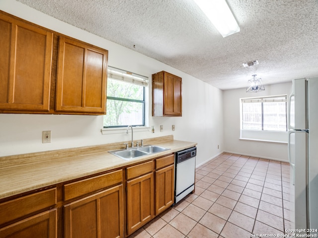 kitchen featuring sink, a textured ceiling, white appliances, and light tile patterned floors