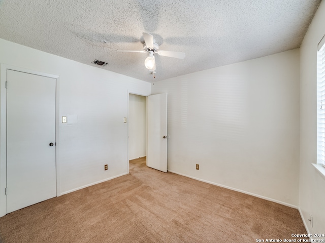 carpeted empty room with a textured ceiling and ceiling fan