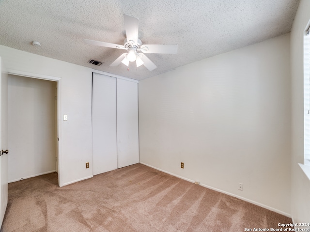 unfurnished bedroom with a closet, a textured ceiling, ceiling fan, and light colored carpet