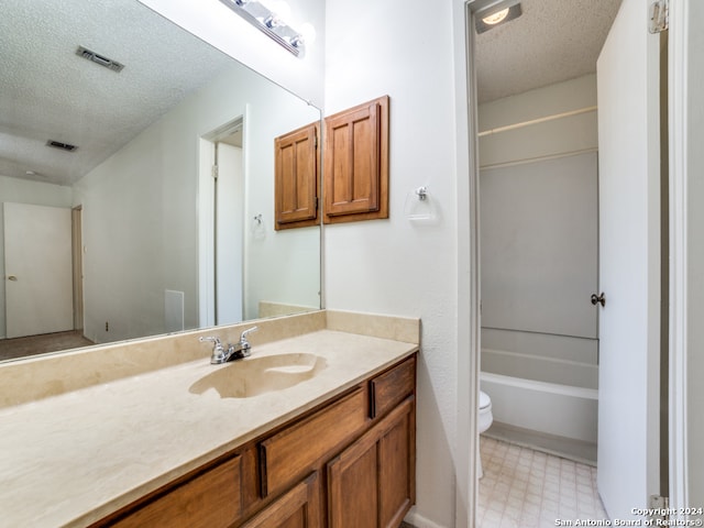 full bathroom with vanity, tile patterned floors, tub / shower combination, toilet, and a textured ceiling