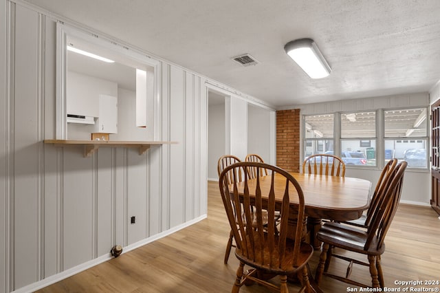 dining room with light hardwood / wood-style flooring and a textured ceiling