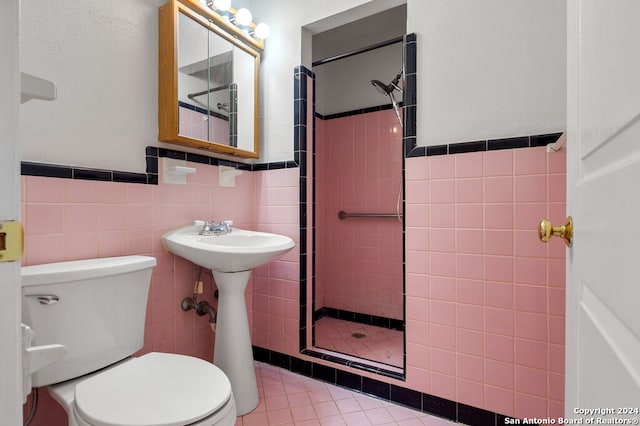 bathroom featuring toilet, tile patterned floors, tile walls, and tiled shower