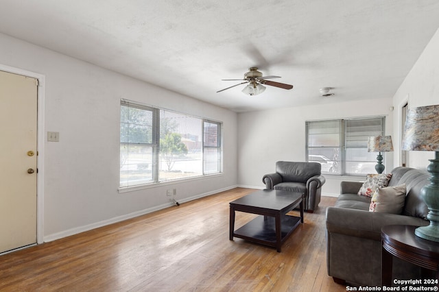 living room with a textured ceiling, light wood-type flooring, and ceiling fan