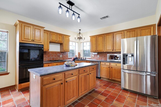 kitchen featuring ceiling fan, dark tile patterned flooring, a kitchen island, and decorative backsplash