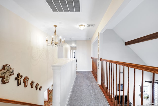 hallway with vaulted ceiling, an inviting chandelier, and carpet floors