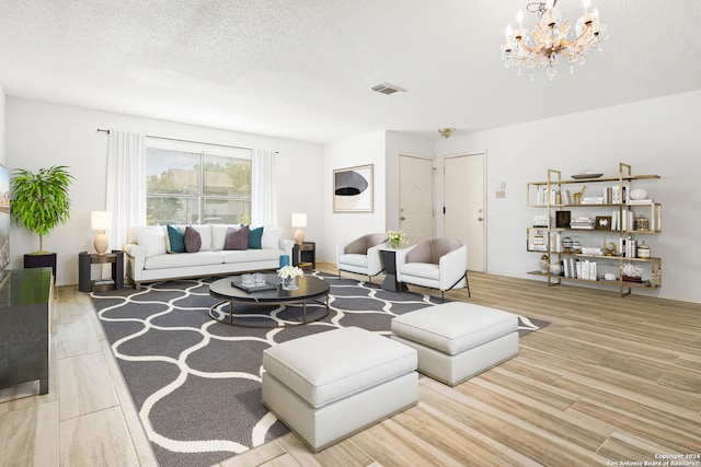 living room with light wood-type flooring, a textured ceiling, and a notable chandelier