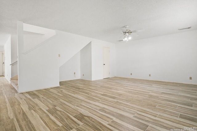 unfurnished living room with a textured ceiling, light hardwood / wood-style flooring, and ceiling fan