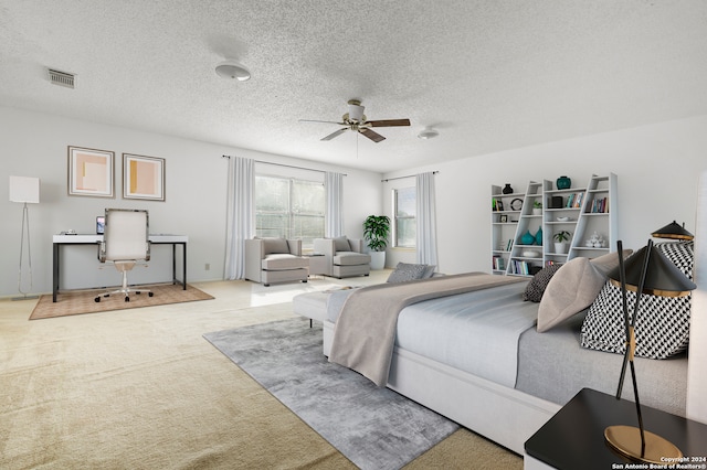 bedroom featuring ceiling fan, light colored carpet, and a textured ceiling