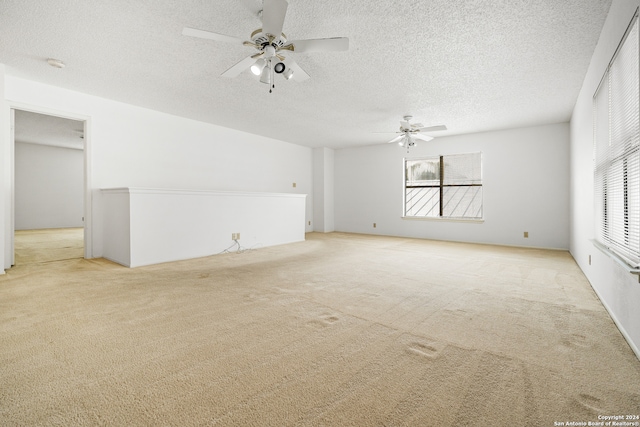 spare room with a textured ceiling, light colored carpet, and ceiling fan