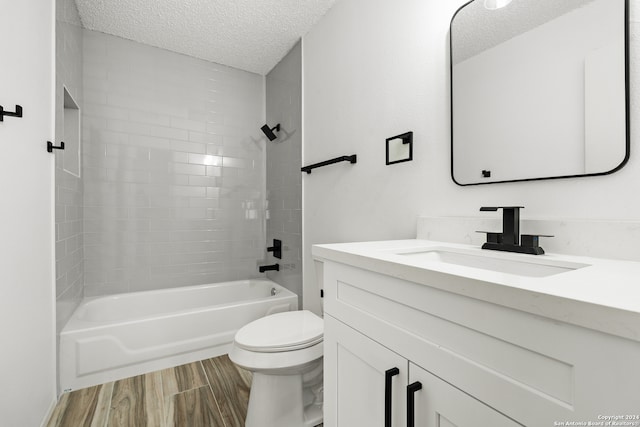 full bathroom featuring vanity, a textured ceiling, tiled shower / bath, and toilet