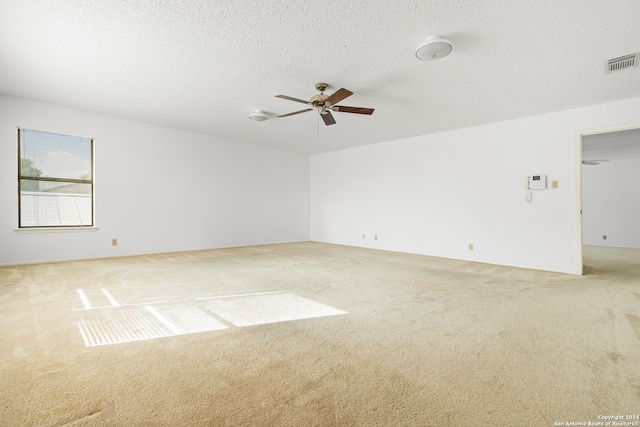 spare room featuring light carpet, a textured ceiling, and ceiling fan