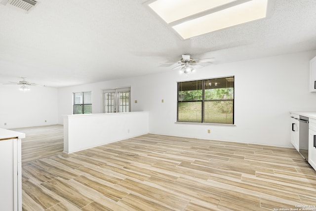 unfurnished living room with light hardwood / wood-style flooring, a textured ceiling, ceiling fan, and french doors