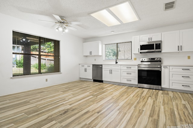 kitchen featuring white cabinets, light hardwood / wood-style flooring, appliances with stainless steel finishes, and ceiling fan