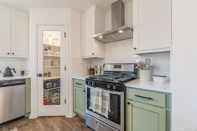 kitchen featuring hardwood / wood-style flooring, tasteful backsplash, wall chimney range hood, stainless steel appliances, and white cabinets