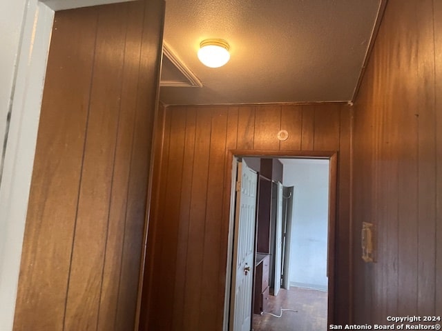 hall with a textured ceiling and wooden walls