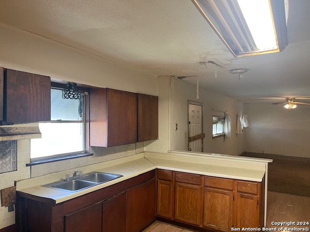 kitchen with sink, light hardwood / wood-style flooring, kitchen peninsula, and ceiling fan