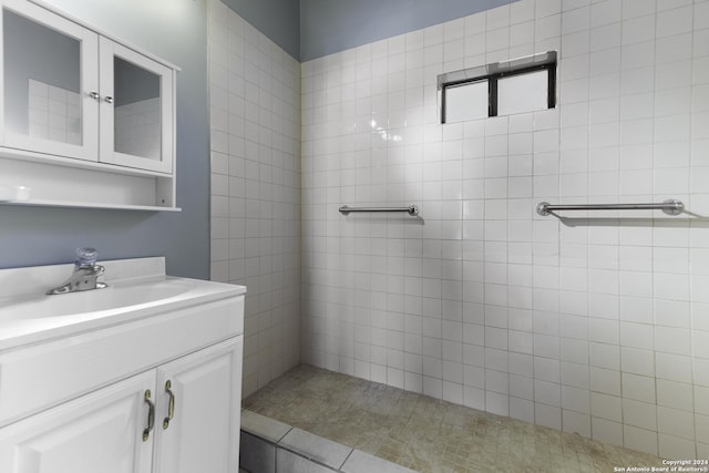 bathroom with tiled shower and vanity