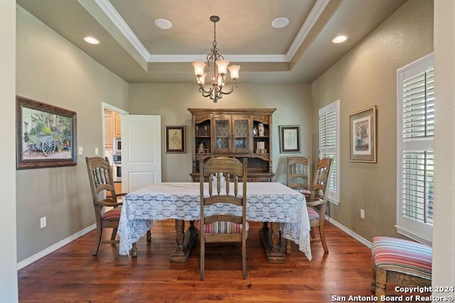 dining room with dark hardwood / wood-style floors, a healthy amount of sunlight, a tray ceiling, and an inviting chandelier