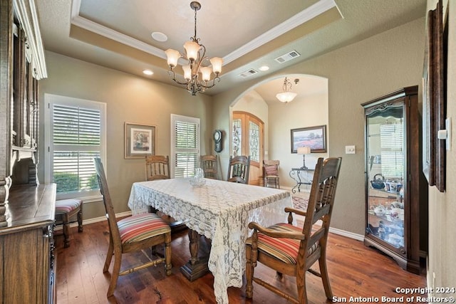 dining space with dark hardwood / wood-style flooring, a notable chandelier, ornamental molding, and a raised ceiling