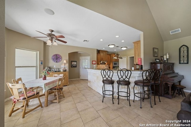 kitchen featuring lofted ceiling, light tile patterned floors, a breakfast bar area, and kitchen peninsula