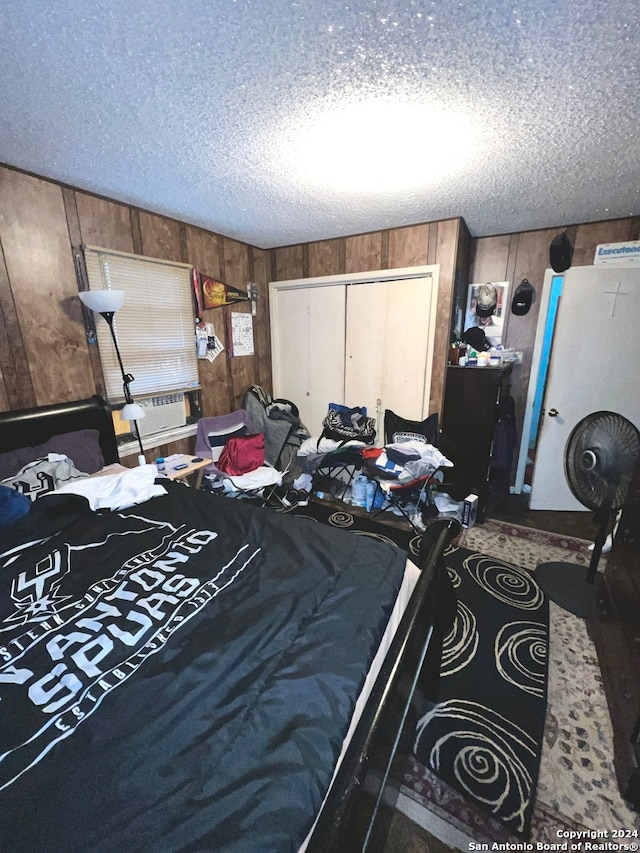 bedroom with carpet floors, wood walls, a textured ceiling, and a closet