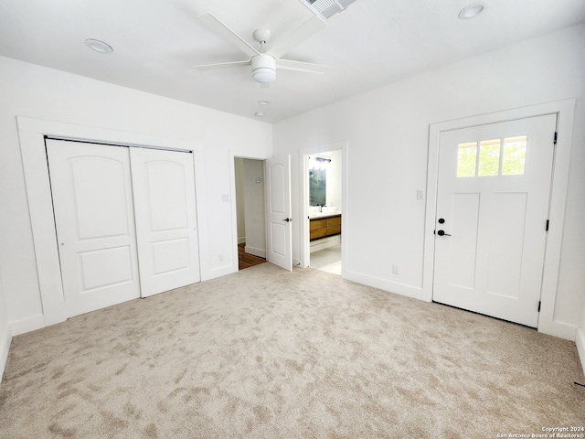 unfurnished bedroom with ensuite bathroom, a closet, ceiling fan, and light colored carpet